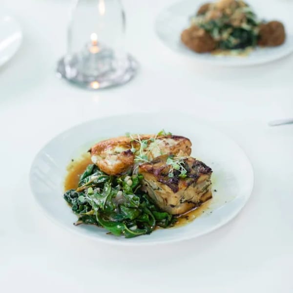 Fable's American cuisine: chicken, potato gratin, and sautéed greens on a white plate.