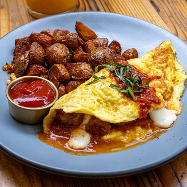 A Fable omelet with meatballs, mozzarella, and tomato sauce, served with roasted potatoes and ketchup.