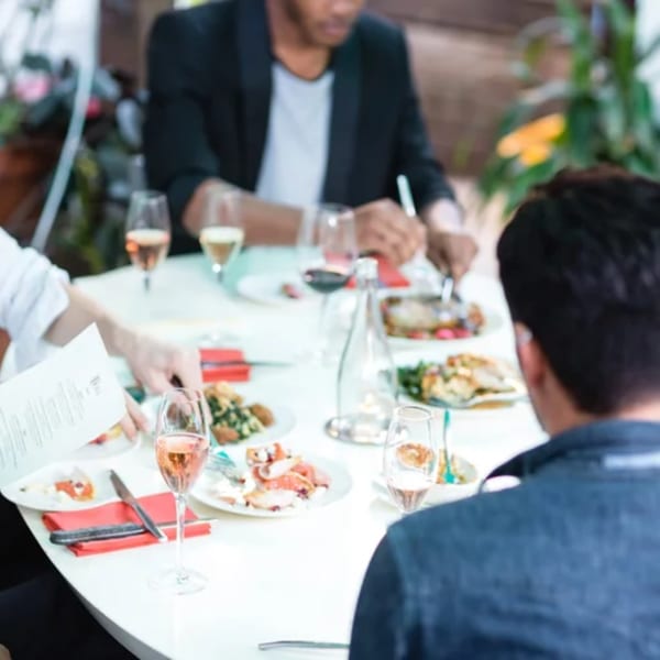 Diners enjoying American cuisine and drinks at a white table in Fable restaurant.