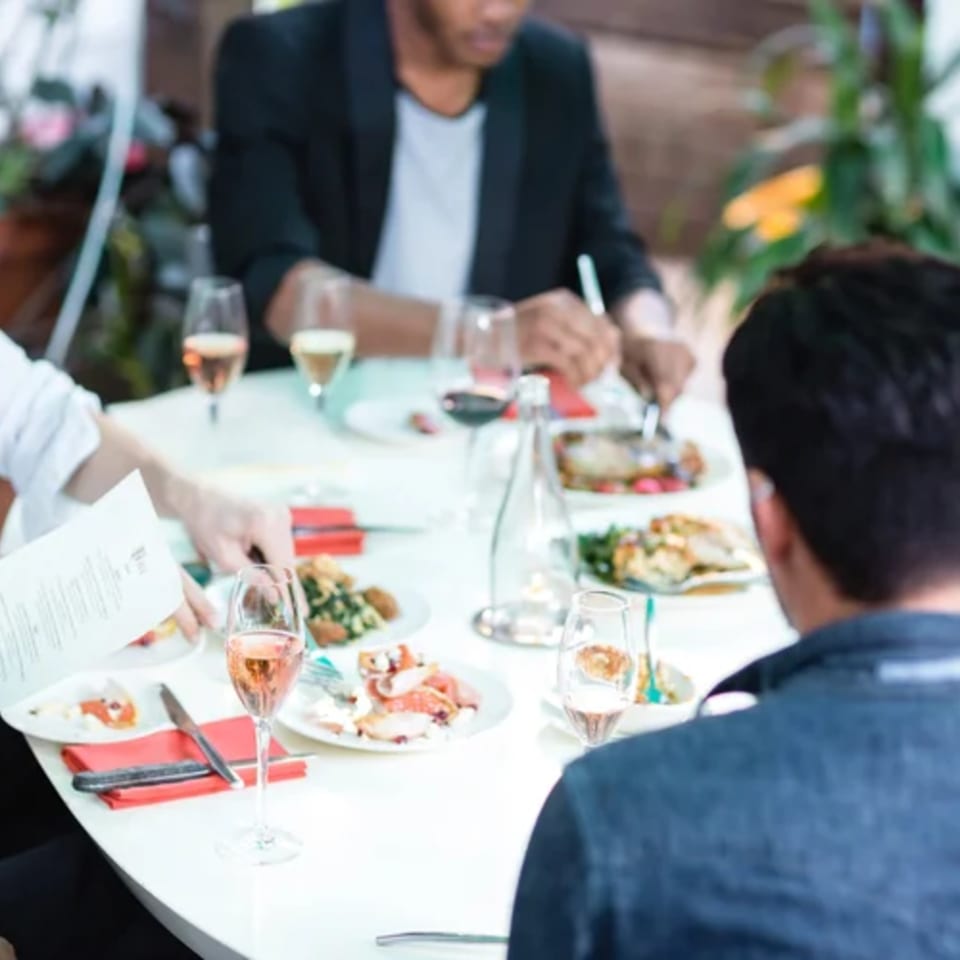 Diners enjoying American cuisine and drinks at a white table in Fable restaurant.
