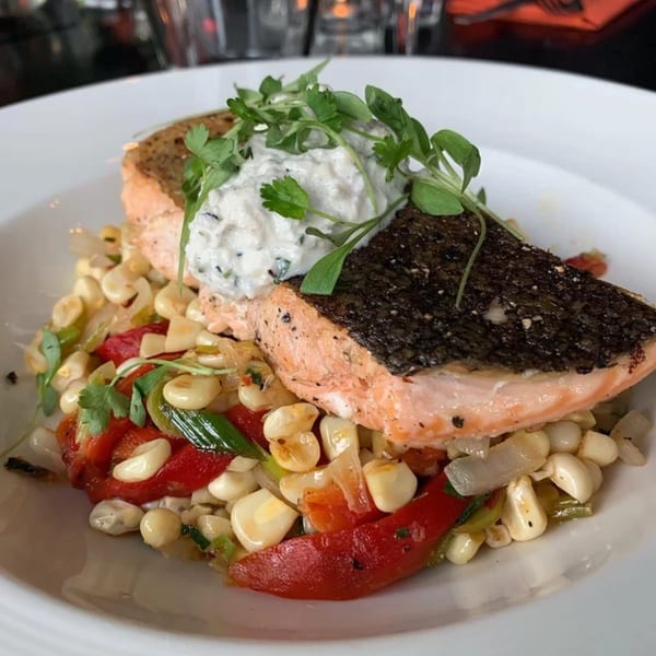 Fable's pan-seared salmon with crispy skin, creamy sauce, and a side of corn and red peppers.