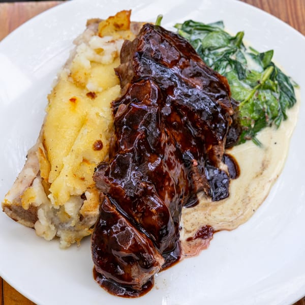 Fable's braised short rib with mashed potatoes and creamed spinach on a white plate.